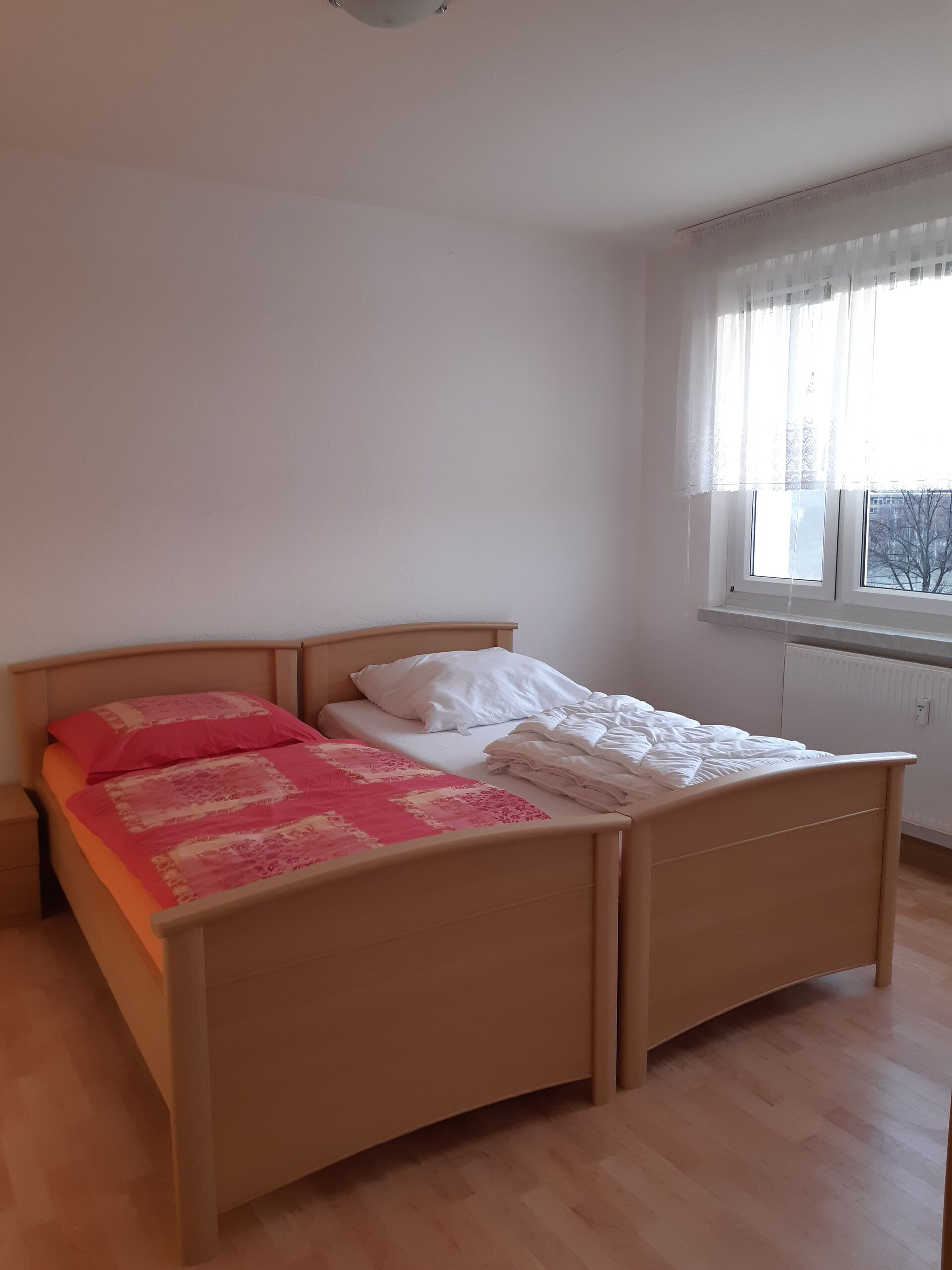 Gästewohnung in Gröditz, Am Kanal 25 - Schlafzimmer mit einem Doppelbett, roter Bettwäsche und einem Stulpfenster