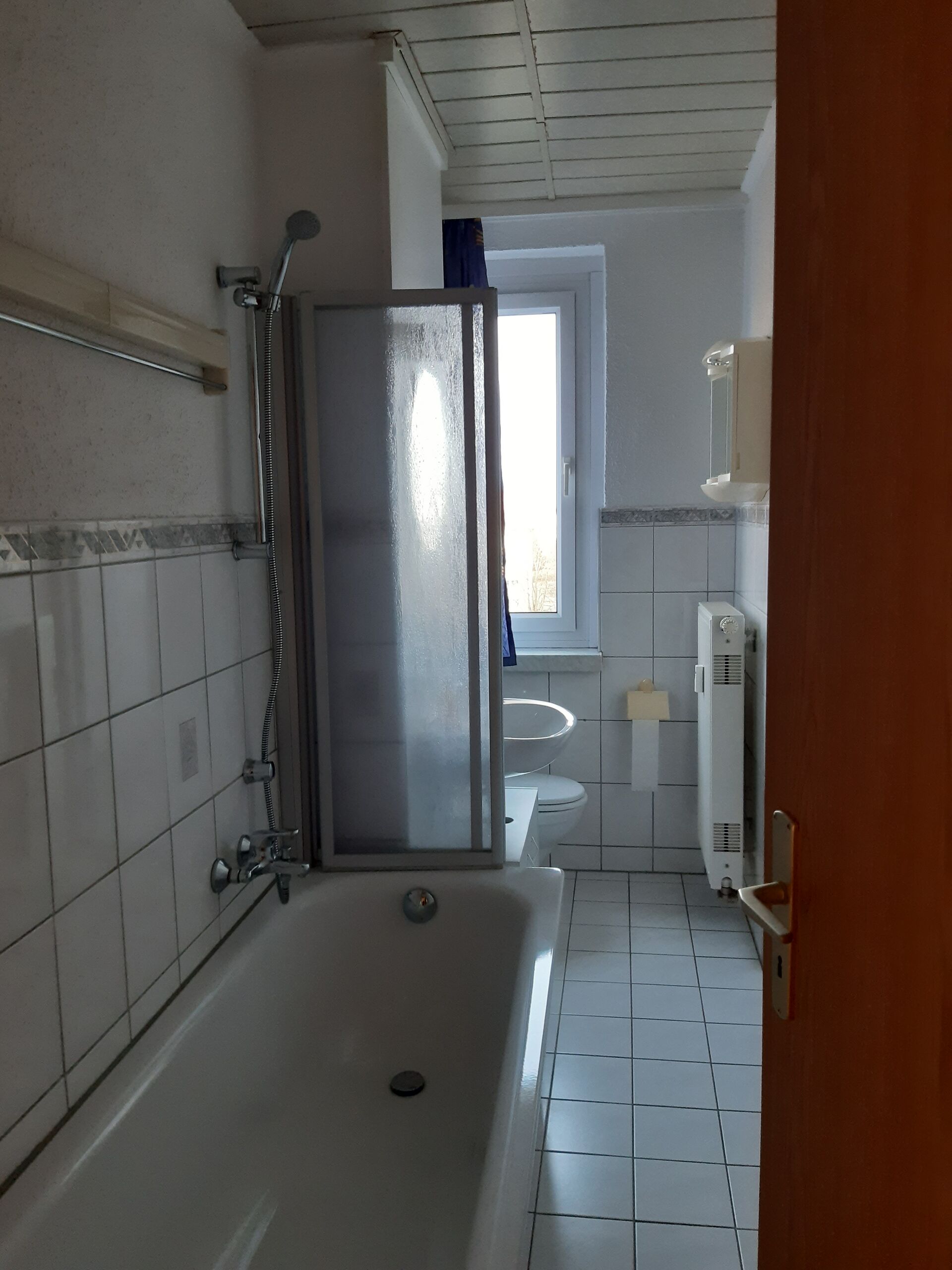 Gästewohnung in Gröditz, Am Kanal 23 - Badezimmer mit Badewanne, Waschbecken, Toilette, Heizung und einem Fenster