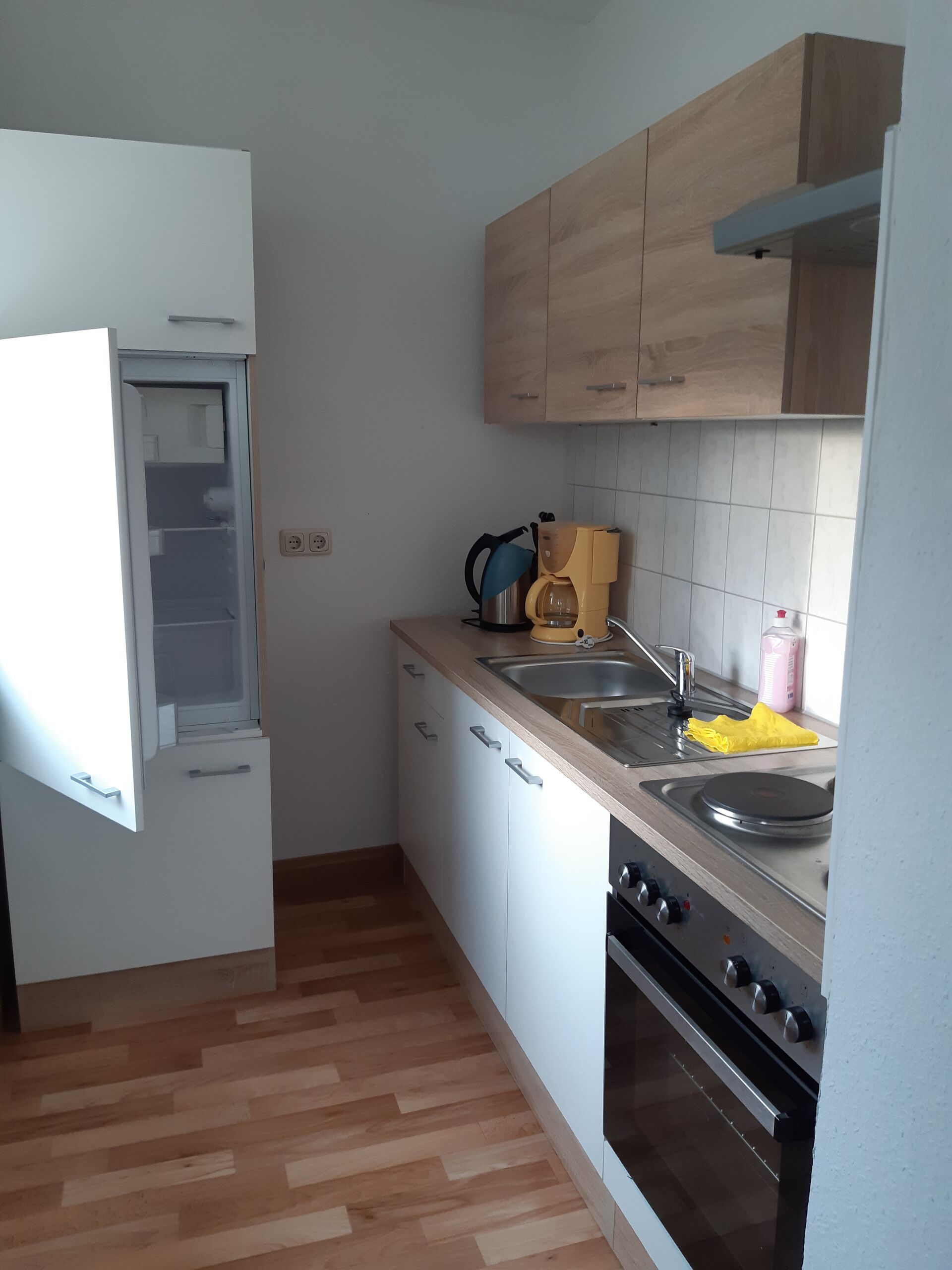 Gästewohnung in Gröditz, Am Kanal 27 - Küche mit weißen Schränke, Waschbecken, Kaffeemaschine, Kühlschrank und Wasserkocher