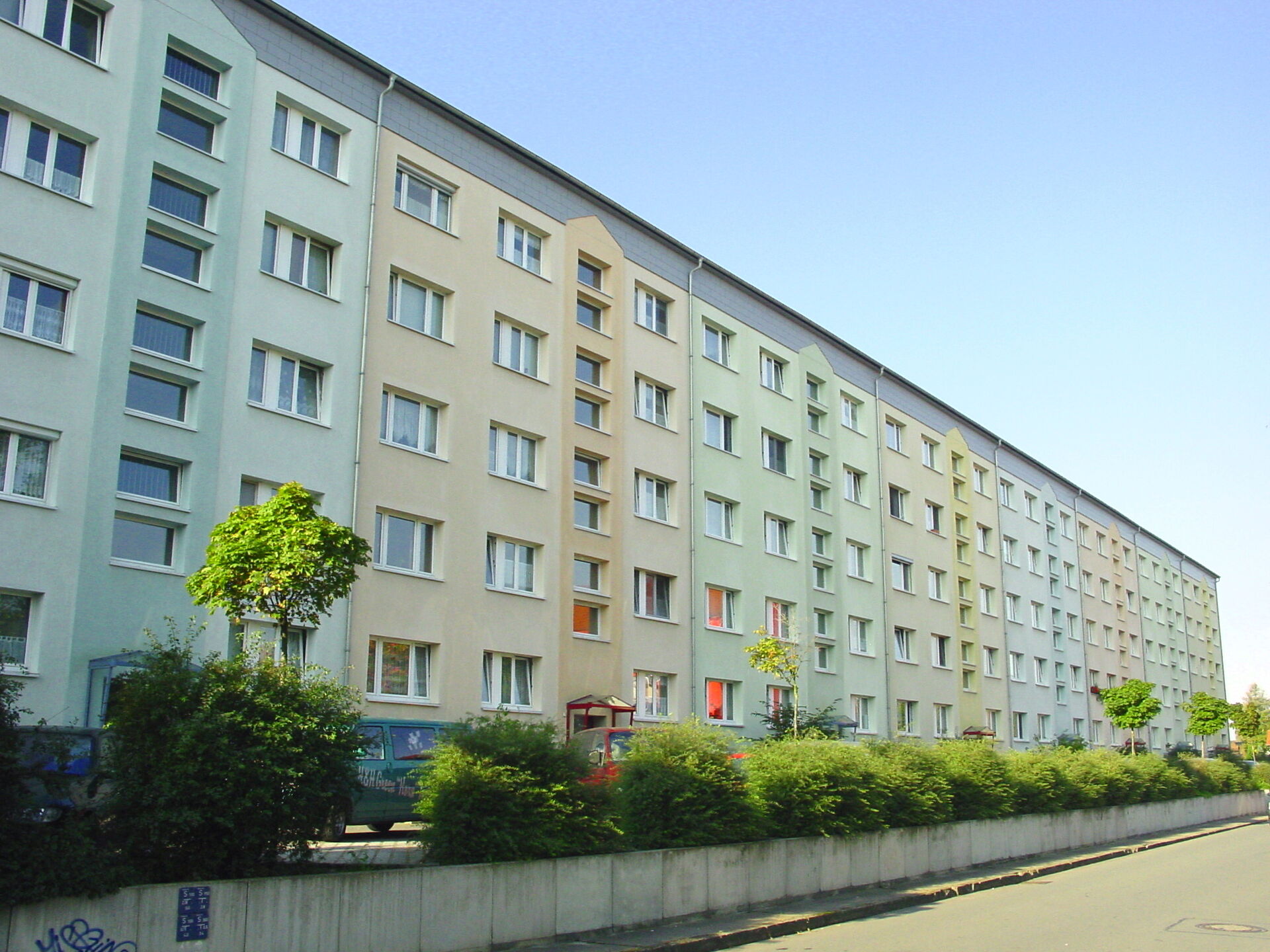 Reihe von mehrstöckigen Wohnhäusern mit Balkonen und einer grünen Anlage davor in Gröditz. Mietwohnungen der KWG.