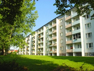 Mehrfamilienhaus in Gröditz mit grüner Wiese und Bäumen, bietet 3-Zimmer-Wohnungen mit Balkon zur Miete durch die KWG.