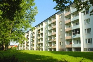 Ein Mehrfamilienhaus mit vielen Balkonen und einer gepflegten grünen Rasenfläche davor in Gröditz. Wohngebäude der KWG.